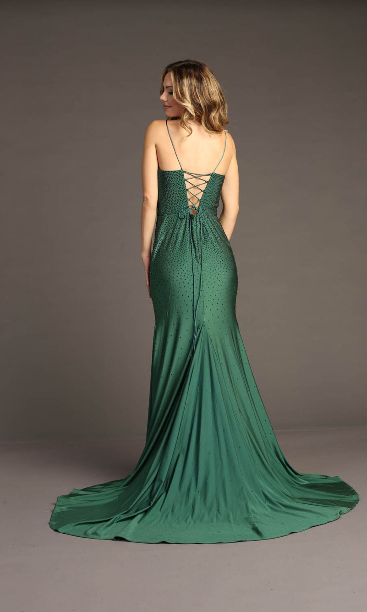 A woman models the Chicas YG5026 Lace-Up Long Beaded Prom Dress, featuring a fitted silhouette with thin straps and a lace-up back, standing against a plain background.